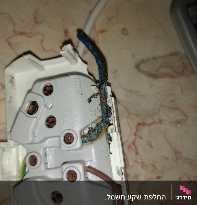 חוטי חשמל שרופים בתוך שקע חשמלי פתוח